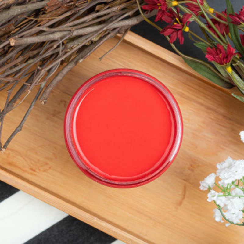 Red round object on a wooden tray with branches and flowers
