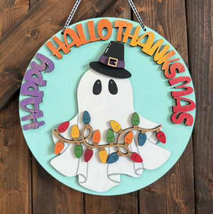 Decorative sign with ghost, witch hat, and 'Happy Hallo Thanksmas' text on a wooden background